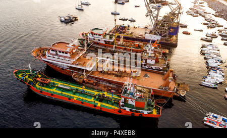 Group of Old Cargo Ships, Tugboats, Fishing Ships and Small Boats in the Coast near Rocks. Transportation. Stock Photo