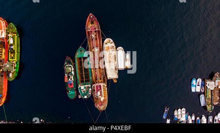 Group of Old Cargo Ships, Tugboats, Fishing Ships and Small Boats in the Coast near Rocks. Transportation. Stock Photo