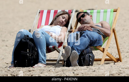 A couple enjoy the warm weather on the beach in Margate, Kent. Stock Photo