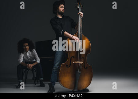 handsome young man playing violoncello while his partner sitting at piano blurred on background Stock Photo