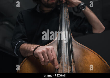 cropped shot of man playing double bass on black Stock Photo