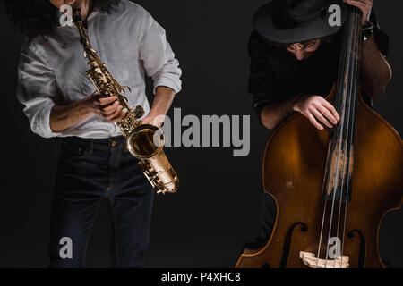 duet of jazzmen playign cello and sax on black Stock Photo