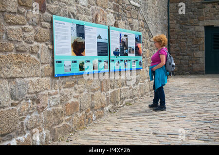 A female tourist reading the interpretation at St. Michael's Mount, Cornwall, UK - John Gollop Stock Photo