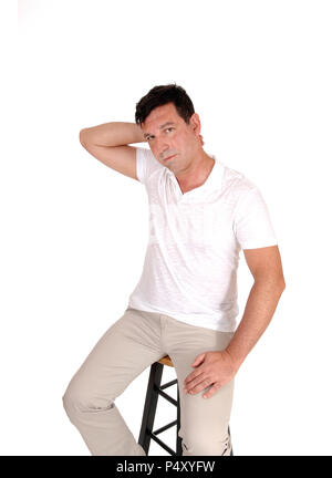 A handsome middle age man sitting on a chair with one hand behind his head looking very serious, isolated for white background Stock Photo