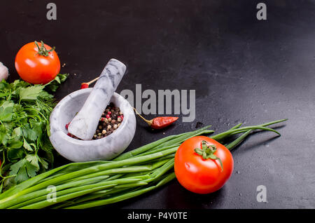 Ripe cherry tomato, green onion and parsley, garlic, solt in spoon and spices on a black background. Top view, Copy space. Stock Photo