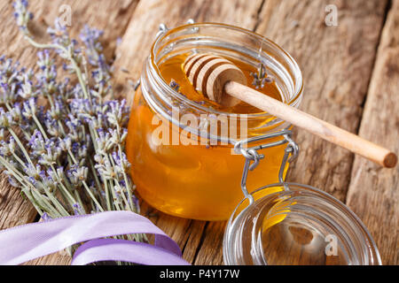 Fresh lavender honey in a glass jar and flowers close-up on a table. horizontal Stock Photo