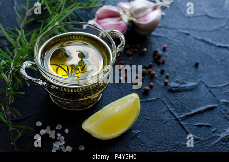 Herbs and spices selection - rosemary, garlic, lemon, salt, peppercorns and olive oil on dark stone table. Creative layout with place for text. Copy s Stock Photo