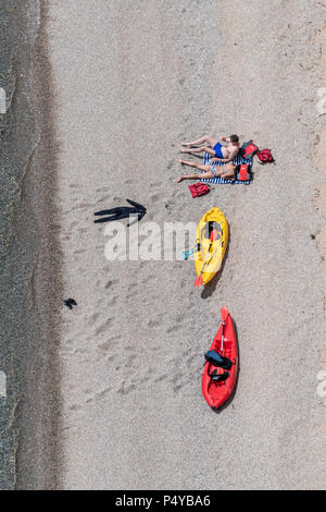 Lulworth, Dorset, UK. 23rd June 2018. Two people relax on the beach with their kayaks at Durdle Door on the Dorset coast, near Lulworth Cove on a hot sunny day in June. Thomas Faull/Alamy Live News Stock Photo