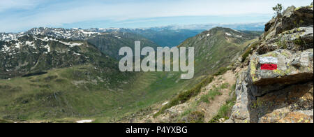 White and red way marker sign painted on a rock in the French Pyrenees next to a footpath on the GR10 hiking trial, with a panoramic view Stock Photo