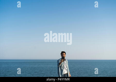 Young man taking selfie with smartphone at the beach Stock Photo