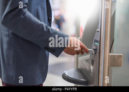 Close-up of businessman withdrawing money at an ATM Stock Photo