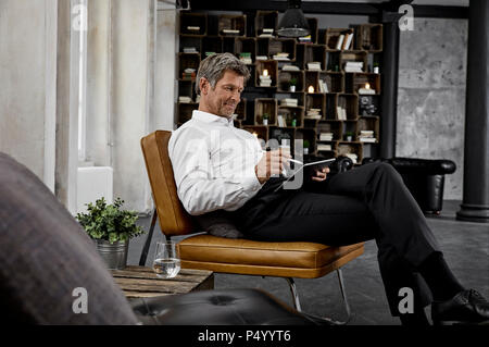 Mature man using digital tablet with digital pen in loft Stock Photo