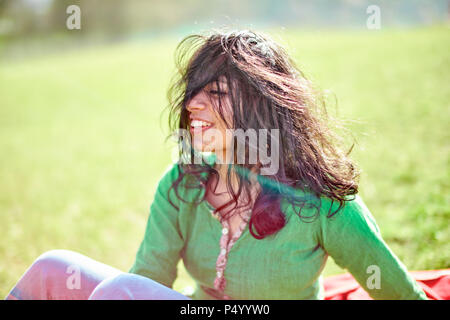 Happy young woman with windswept hair on a meadow Stock Photo