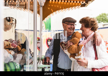 Happy senior couple with prize on fair Stock Photo