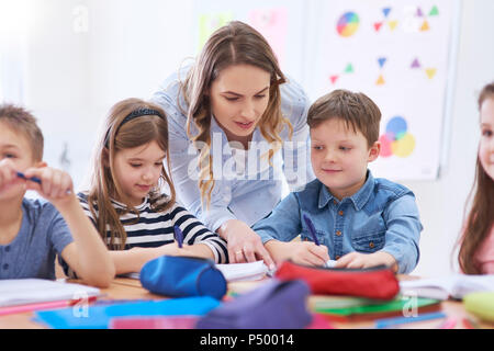 Teacher helping pupils with their tasks in class Stock Photo