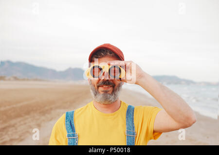 Bearded man using binoculars on the beach Stock Photo