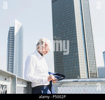 Mature businessman in the city using cell phone Stock Photo