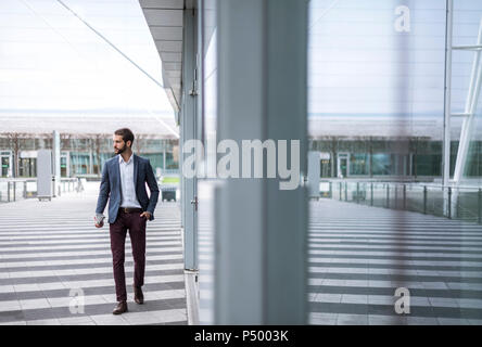 Young businessman on the go at building with glass facade Stock Photo
