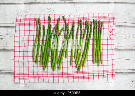 Organic green asparagus on red-white kitchen towel Stock Photo