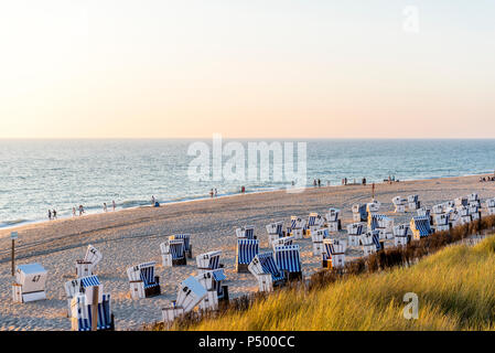 Germany, Schleswig-Holstein, Sylt, beach and empty hooded beach chairs at sunset Stock Photo