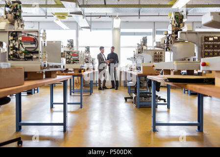 Two businessmen with tablet talking in factory Stock Photo