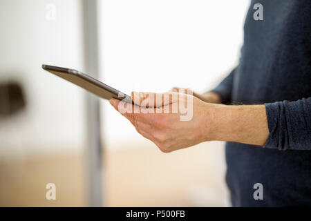 Mature man standing in his office, using digital tablet Stock Photo