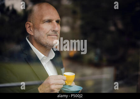 Senior businessman standing by window, drinking coffee Stock Photo