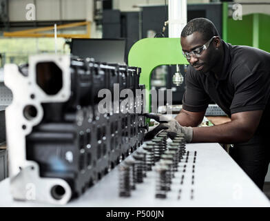 Worker in metalworking factory loading cylinder head Stock Photo
