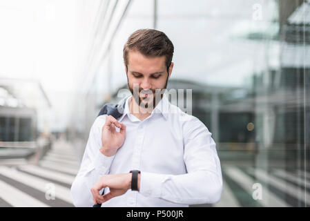 Smiling young businessman checking the time Stock Photo