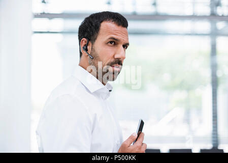 Businessman using smartphone and headset Stock Photo