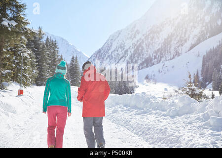 Couple walking in snow-covered landscape Stock Photo