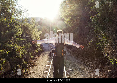 Greece, Pilion, Milies, back view of man with backpack balancing along rails of Narrow Gauge Railway Stock Photo