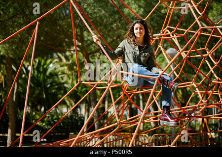 Portrait of young woman on a climbing frame on a playground Stock Photo
