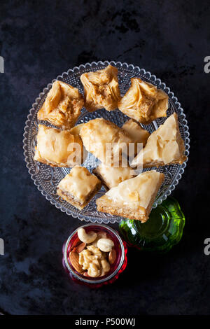 Baklava on cake stand and bowl of nuts on dark ground Stock Photo