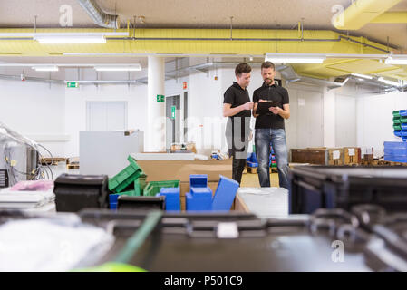 Two men with clipboard talking in factory Stock Photo