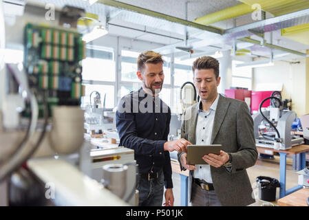 Two businessmen with tablet talking in factory Stock Photo
