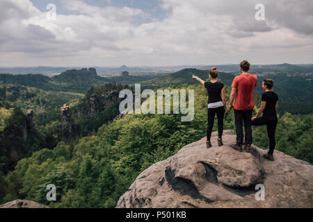 Germany, Saxony, Elbe Sandstone Mountains, friends on a hiking trip standing on rock Stock Photo