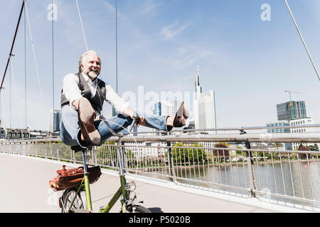 Playful mature man on bicycle on bridge in the city Stock Photo
