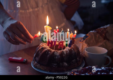 Woman lightning birthday cake candles, partial view Stock Photo