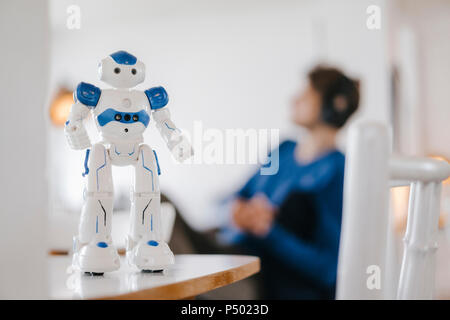 Robot on table with man in background Stock Photo