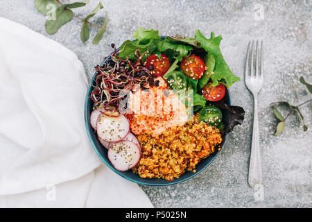 Vegan buddha bowl with hummus, quinoa with curry, lettuce, sprouts, green and red cherry tomatoes, sliced radish and sesame and poppy seeds Stock Photo