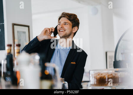 Smiling man in a cafe talking on cell phone Stock Photo