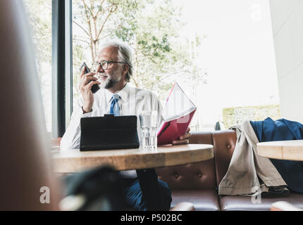 Smiling mature businessman working at table in a cafe Stock Photo