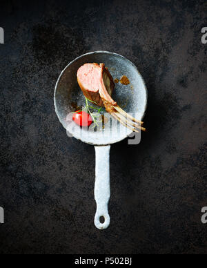 Rack of lamb in sauce pan with tomato and herbs Stock Photo