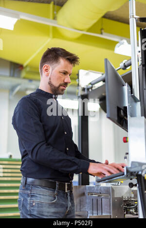 Man in factory operating machine Stock Photo