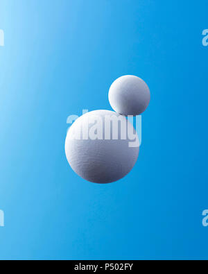 Two white spheres in front of blue background Stock Photo