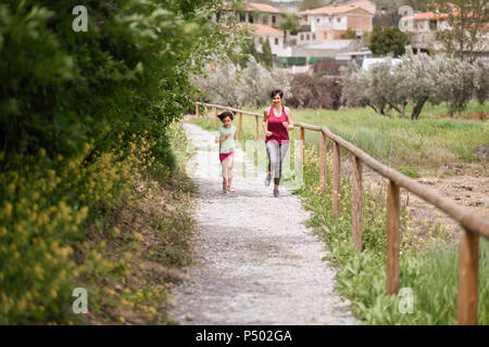 Mother and daughter running on a path in nature enviroment Stock Photo