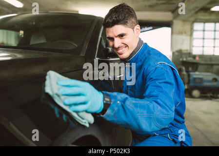 Smiling man cleaning a car in a workshop Stock Photo