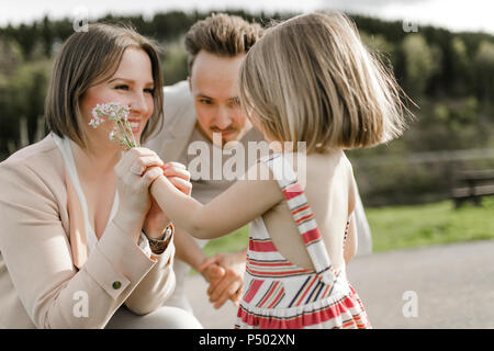 Little girl giving mother flowers while her father is watching Stock Photo