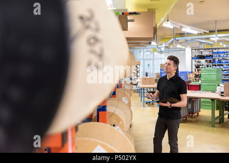 Man with clipboard in factory taking notes Stock Photo